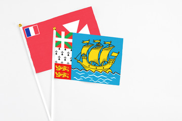 Saint Pierre And Miquelon and Wallis And Futuna stick flags on white background. High quality fabric, miniature national flag. Peaceful global concept.White floor for copy space.