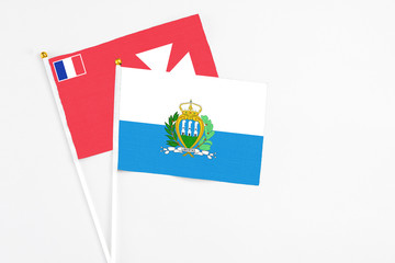 San Marino and Wallis And Futuna stick flags on white background. High quality fabric, miniature national flag. Peaceful global concept.White floor for copy space.