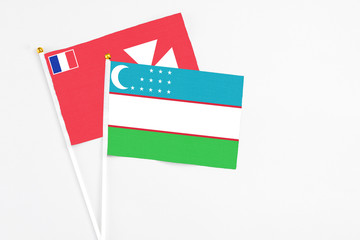 Uzbekistan and Wallis And Futuna stick flags on white background. High quality fabric, miniature national flag. Peaceful global concept.White floor for copy space.