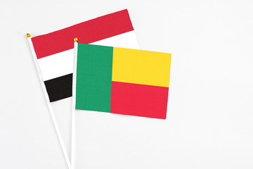 Benin and Yemen stick flags on white background. High quality fabric, miniature national flag. Peaceful global concept.White floor for copy space.