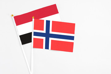 Bouvet Islands and Yemen stick flags on white background. High quality fabric, miniature national flag. Peaceful global concept.White floor for copy space.