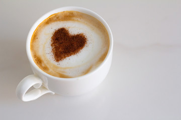 white cup with coffee and a patterned heart on milk foam
