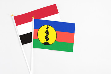 New Caledonia and Yemen stick flags on white background. High quality fabric, miniature national flag. Peaceful global concept.White floor for copy space.