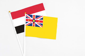 Niue and Yemen stick flags on white background. High quality fabric, miniature national flag. Peaceful global concept.White floor for copy space.