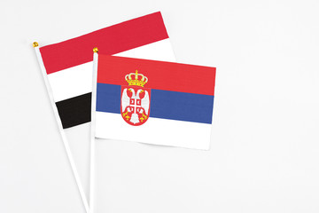 Serbia and Yemen stick flags on white background. High quality fabric, miniature national flag. Peaceful global concept.White floor for copy space.