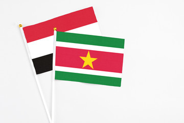 Suriname and Yemen stick flags on white background. High quality fabric, miniature national flag. Peaceful global concept.White floor for copy space.