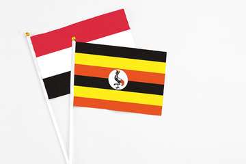 Uganda and Yemen stick flags on white background. High quality fabric, miniature national flag. Peaceful global concept.White floor for copy space.
