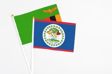 Belize and Zambia stick flags on white background. High quality fabric, miniature national flag. Peaceful global concept.White floor for copy space.
