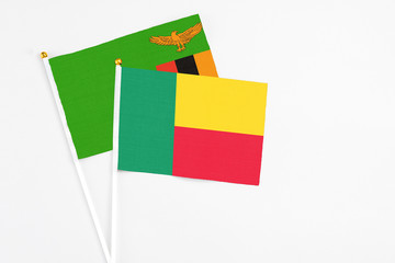 Benin and Zambia stick flags on white background. High quality fabric, miniature national flag. Peaceful global concept.White floor for copy space.