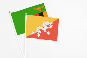 Bhutan and Zambia stick flags on white background. High quality fabric, miniature national flag. Peaceful global concept.White floor for copy space.