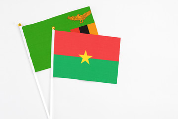 Burkina Faso and Zambia stick flags on white background. High quality fabric, miniature national flag. Peaceful global concept.White floor for copy space.