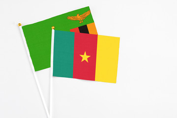 Fototapeta premium Cameroon and Zambia stick flags on white background. High quality fabric, miniature national flag. Peaceful global concept.White floor for copy space.