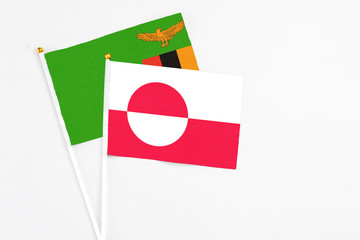 Greenland and Zambia stick flags on white background. High quality fabric, miniature national flag. Peaceful global concept.White floor for copy space.