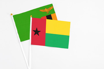 Guinea Bissau and Zambia stick flags on white background. High quality fabric, miniature national flag. Peaceful global concept.White floor for copy space.