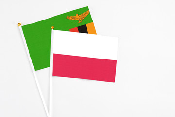 Poland and Zambia stick flags on white background. High quality fabric, miniature national flag. Peaceful global concept.White floor for copy space.