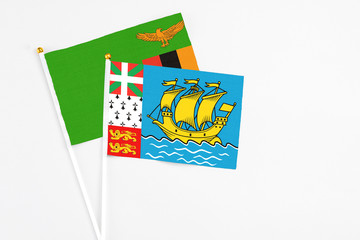 Saint Pierre And Miquelon and Zambia stick flags on white background. High quality fabric, miniature national flag. Peaceful global concept.White floor for copy space.