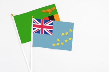 Fototapeta premium Tuvalu and Zambia stick flags on white background. High quality fabric, miniature national flag. Peaceful global concept.White floor for copy space.