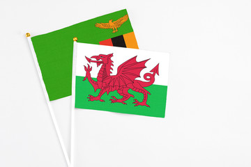 Wales and Zambia stick flags on white background. High quality fabric, miniature national flag. Peaceful global concept.White floor for copy space.