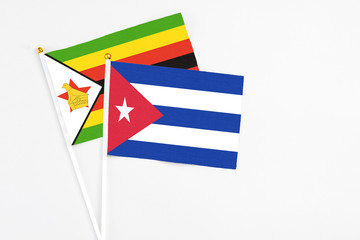 Cuba and Zimbabwe stick flags on white background. High quality fabric, miniature national flag. Peaceful global concept.White floor for copy space.