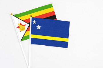 Curacao and Zimbabwe stick flags on white background. High quality fabric, miniature national flag. Peaceful global concept.White floor for copy space.