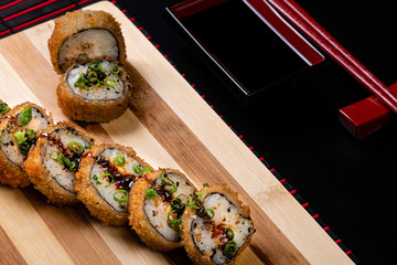 Hot fried Sushi Roll with Salmon and Cheese. Sushi menu. Japanese food On bamboo cutting board to be served.