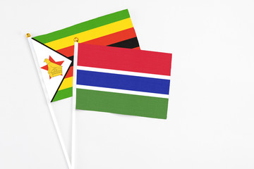 Gambia and Zimbabwe stick flags on white background. High quality fabric, miniature national flag. Peaceful global concept.White floor for copy space.