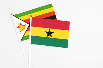 Ghana and Zimbabwe stick flags on white background. High quality fabric, miniature national flag. Peaceful global concept.White floor for copy space.