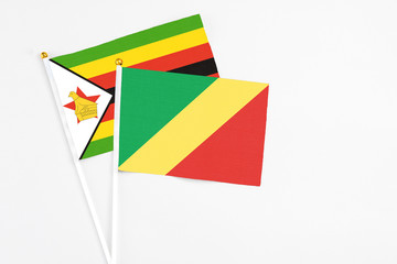 Republic Of The Congo and Zimbabwe stick flags on white background. High quality fabric, miniature national flag. Peaceful global concept.White floor for copy space.