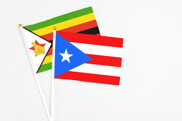 Puerto Rico and Zimbabwe stick flags on white background. High quality fabric, miniature national flag. Peaceful global concept.White floor for copy space.