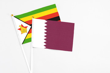 Qatar and Zimbabwe stick flags on white background. High quality fabric, miniature national flag. Peaceful global concept.White floor for copy space.