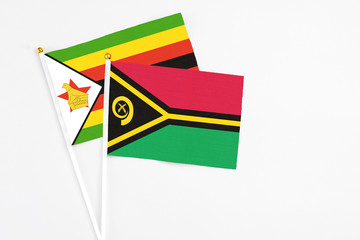 Vanuatu and Zimbabwe stick flags on white background. High quality fabric, miniature national flag. Peaceful global concept.White floor for copy space.