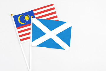 Fototapeta na wymiar Scotland and Malaysia stick flags on white background. High quality fabric, miniature national flag. Peaceful global concept.White floor for copy space.