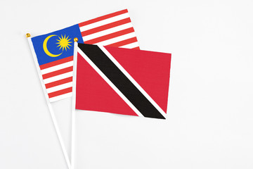 Trinidad And Tobago and Malaysia stick flags on white background. High quality fabric, miniature national flag. Peaceful global concept.White floor for copy space.