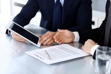 Business people using tablet computer while working together at the desk in modern office. Unknown businessman or male entrepreneur with colleague at workplace. Teamwork and partnership concept