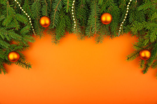 Orange christmas card with free space. branches of spruce with balls on an orange background