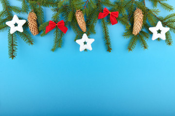 decorated Christmas tree branches on a blue background with copy space.