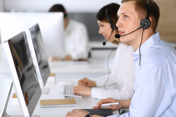 Obraz na płótnie Canvas Call center. Group of diverse operators at work. Focus on businessman in headset at customer service office. Business concept