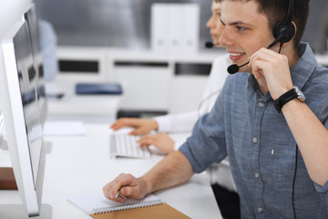 Call center. Group of casual dressed operators at work. Focus on businessman in headset at customer service office. Telesales in business