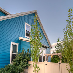 Square Blue timber clad house with neat fenced garden