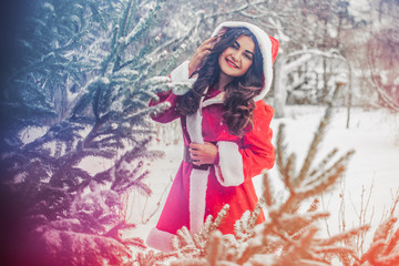 Fototapeta premium Young arabic woman at winter day in pretty Santa coat on a snowy yard