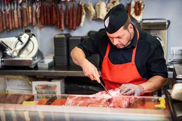Butcher boning fresh ham in a modern butcher shop