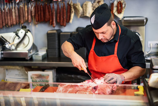 Butcher boning fresh ham in a modern butcher shop