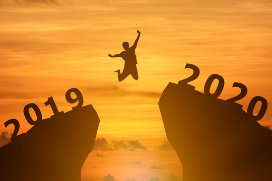 Concept Happy new year 2020 Silhouette image of happy man jump from 2019 up to 2020 on beautiful sky.