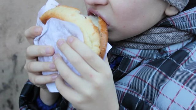 eating a hamburger in winter,boy close up eating hamburger in winter outdoors