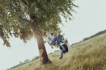 Happy brothers swing on the wheel, summer. Communicate and play together in nature