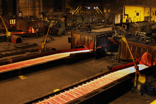 Coiling hot wire rod in a steelworks rolling mill.