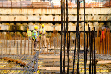Industrial background. Focused view of rusty rebars for concrete pouring. Steel reinforcement bars. Construction workers on the back prepare and check reinforcement bars before pouring cement.