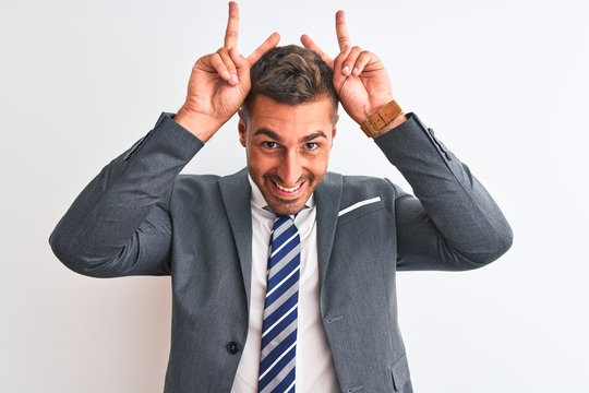 Young handsome business man wearing suit and tie over isolated background Posing funny and crazy with fingers on head as bunny ears, smiling cheerful