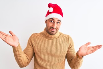 Naklejka premium Young handsome man wearing christmas and turtleneck sweater over isolated background clueless and confused expression with arms and hands raised. Doubt concept.
