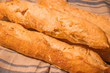 French baguettes on linen towel in morning sunshine. Food background